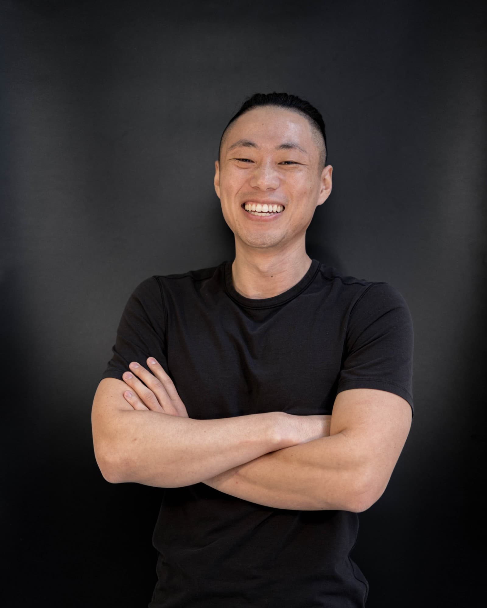 Victor, founder of VHive, smiling with arms crossed against a dark background